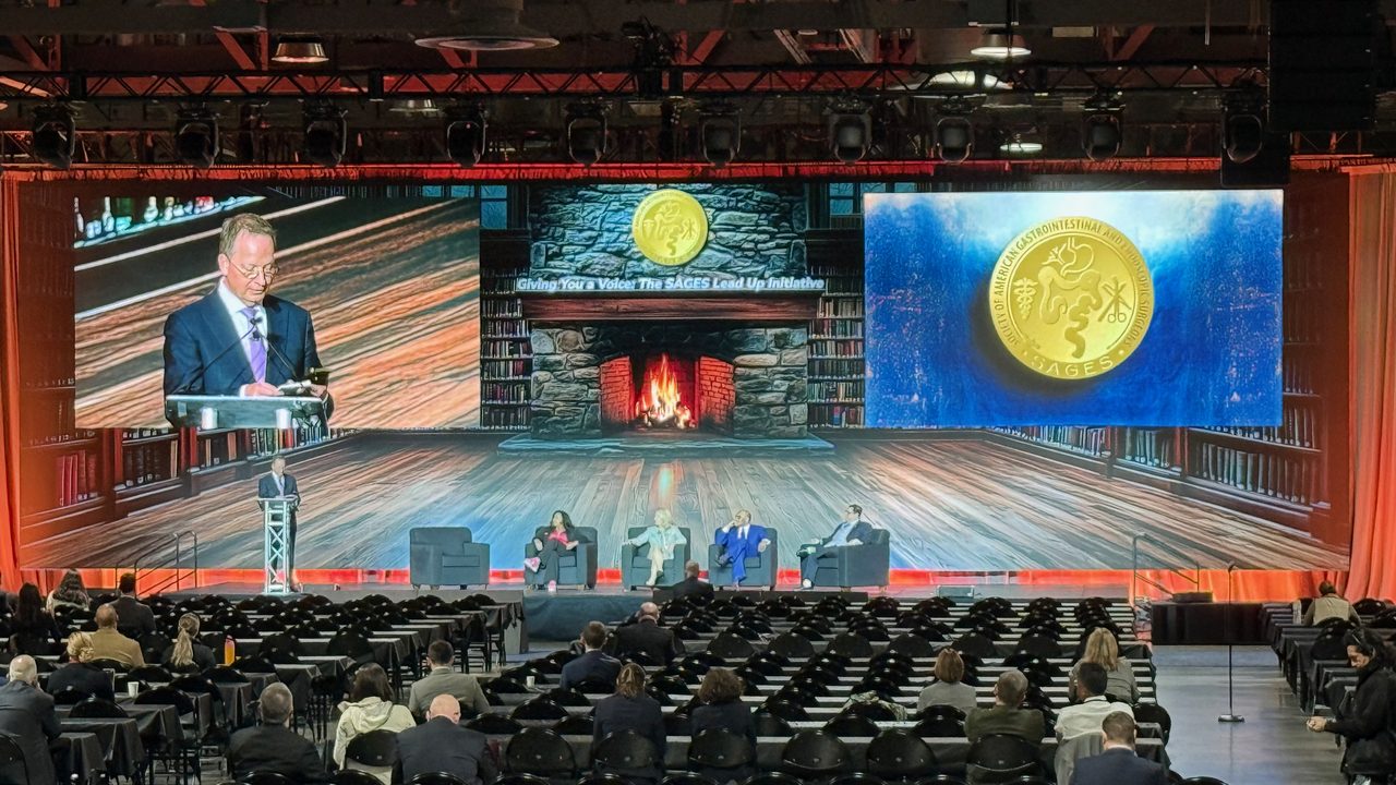 Panel discussion on stage with library and fireplace LED backdrop