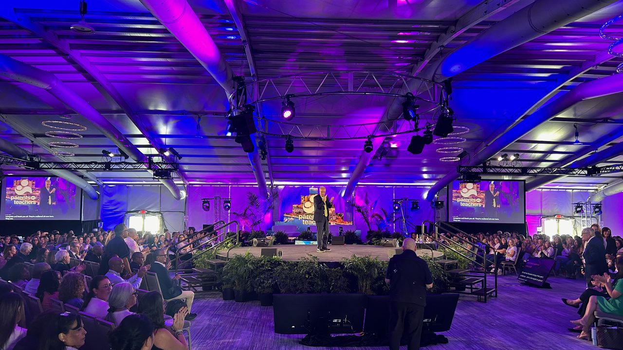 In-the-round general session with purple wash lighting and packed crowd